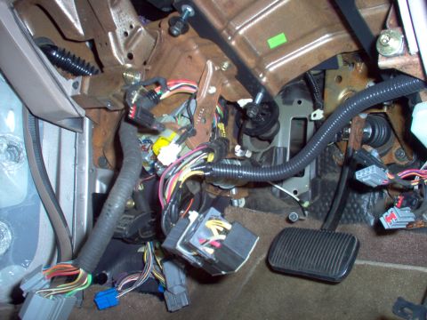 1994 Ford Crown Victoria - The complex network of wires and connectors under the dashboard of a vehicle is visible, along with the brake and accelerator pedals.