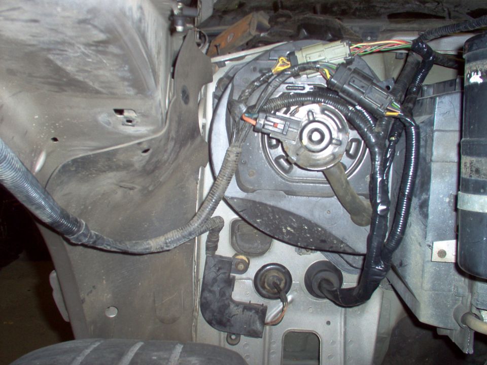 Engine bay component with black wiring harness and connectors on a dusty firewall