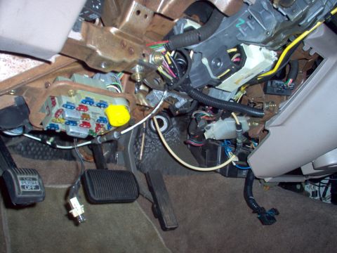 1994 Ford Crown Victoria - Close-up of vehicle's under-dash wiring and fuse box, with pedals visible.