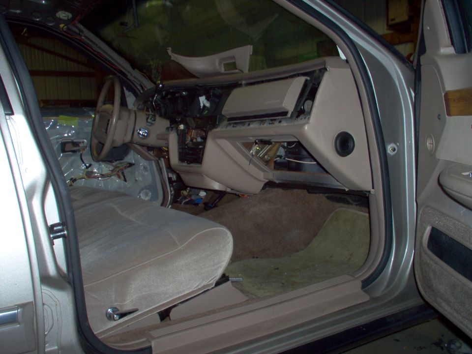 Beige sedan interior with disassembled dashboard viewed through open driver's door