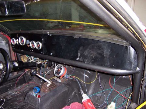 1971 Ford Mustang - The interior of a car is shown with a custom dashboard, roll cage, and extensive wiring, indicating a project in progress.
