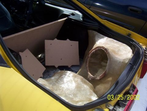 1994 Ford Probe - Custom fiberglass subwoofer enclosure being installed in the trunk of a yellow car.
