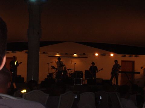 1988 Ford Bronco - A band plays on a stage illuminated by lights, with an audience seated in the foreground.
