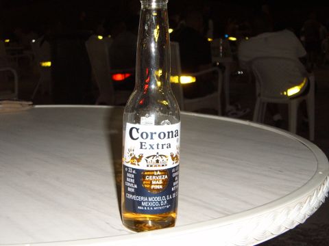 1988 Ford Bronco - A bottle of Corona Extra sits on a table at night, with a blurred background.