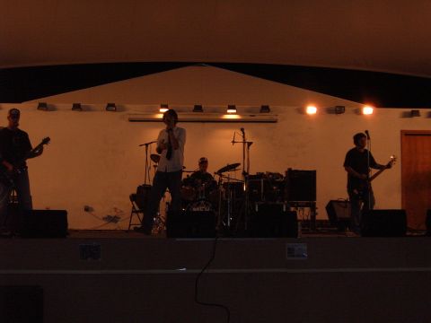 1988 Ford Bronco - A band plays music on a stage under warm lights, with instruments and microphones visible.