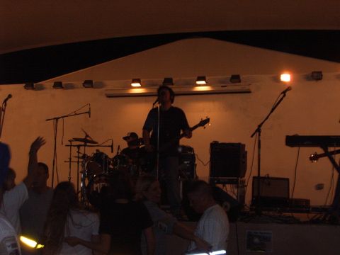 1988 Ford Bronco - A band plays music on a stage with a drummer and guitarist visible, while an audience watches.