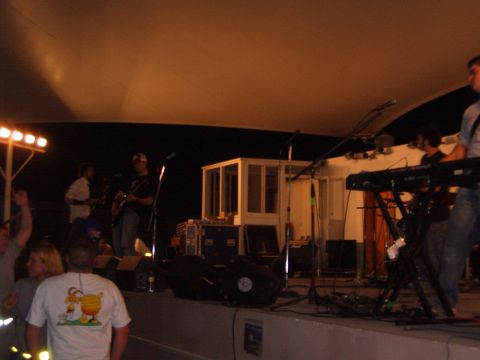 1988 Ford Bronco - A band plays music on a stage under a large canopy, with audience members in the foreground.