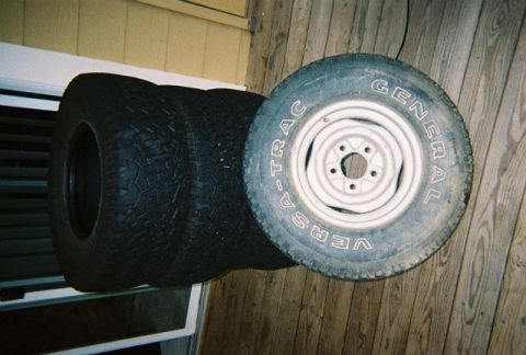 1988 Ford Bronco - Four tires are stacked, with one tire a white rim and General Grabber AT2 tread visible.