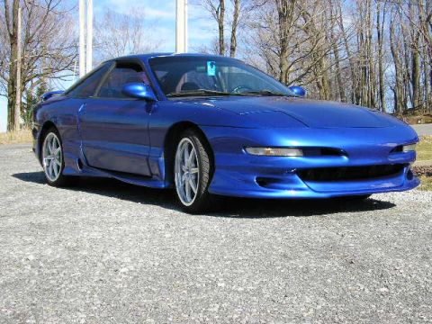 1994 Ford Probe - A bright blue 1994 Ford Probe GT with a custom body kit is parked on a gravel lot.