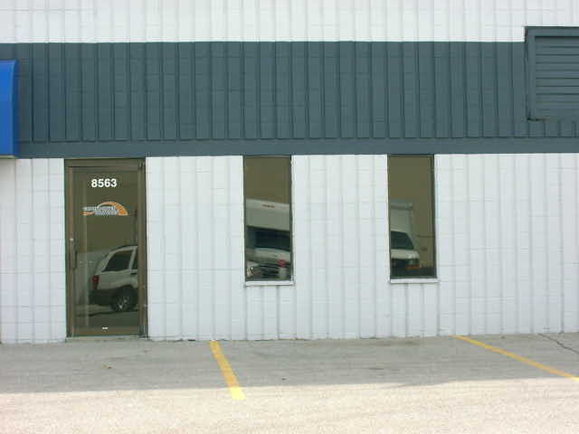 White SUV parked inside a building, seen through a glass door