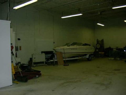 1999 Jeep Grand Cherokee - A white boat rests on a trailer within a large, dimly lit industrial space.