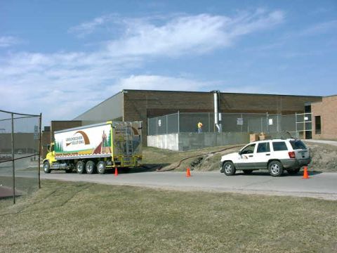 1999 Jeep Grand Cherokee - A white Jeep Grand Cherokee and a semi-trailer truck are seen on a road near a building.