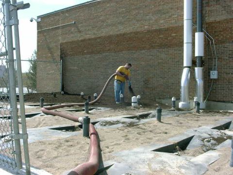 1999 Jeep Grand Cherokee - A worker operates a hose on a construction site, surrounded by pipes and sandy ground.