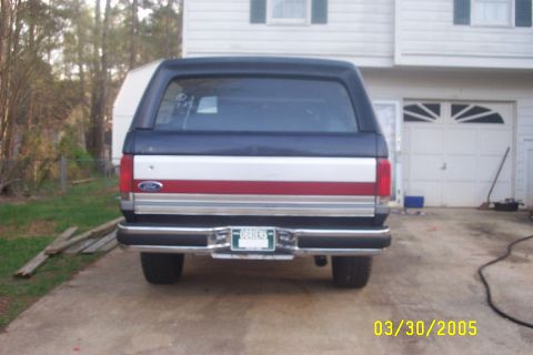 1979 Ford F-150 - 1987 Ford Bronco rear view, parked in driveway with garage and house in background.