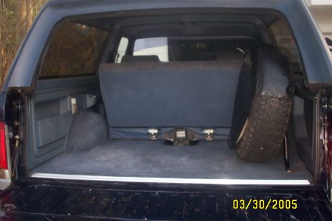 1979 Ford F-150 - The rear interior of a dark blue SUV is visible, a spare tire and a folded rear seat.