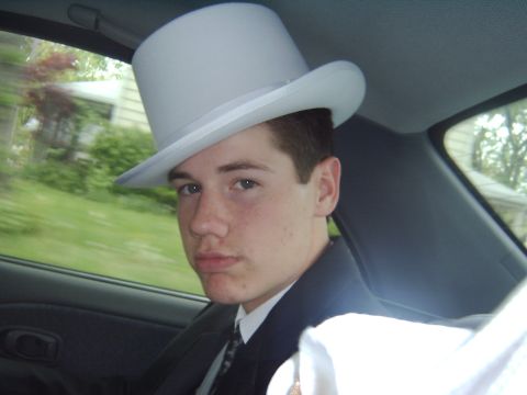 1998 Jeep TJ - A young man in formal attire and a top hat is a passenger in a vehicle.