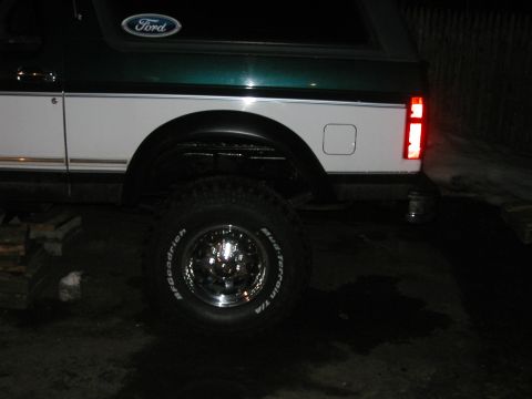 1994 Ford Bronco - The rear quarter panel and tire of a Ford Bronco are visible in this nighttime shot.