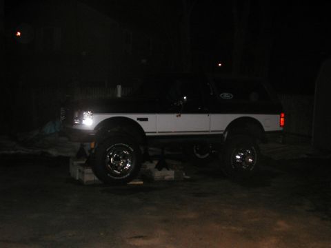 1994 Ford Bronco - This lifted Ford Bronco is parked on blocks at night.