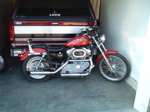 1995 Mercury Grand Marquis - A red Harley-Davidson motorcycle is parked in a garage next to a pickup truck with a Leer cap.
