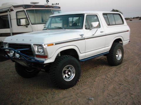 1978 Ford Bronco - This 1978 Ford Bronco is parked on sandy terrain, with a large RV visible in the background.