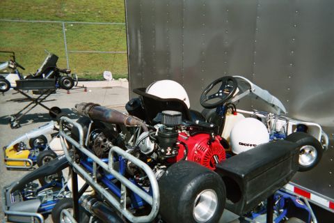 1990 Ford Bronco - Close-up of a racing go-kart showing its exposed engine, exhaust and slick rear tires, with a white helmet resting on the seat.