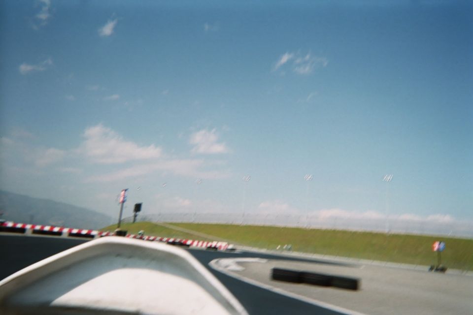 Blurry forward view over a go-kart nose on a track curve with mountains