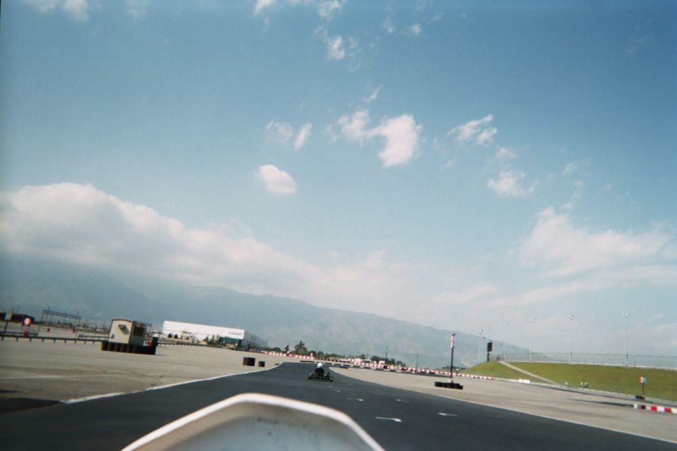 View over a go-kart nose down a long track toward mountains