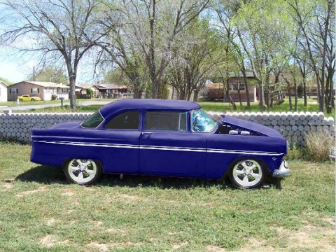 1955 Ford Customline - Side view of a 1955 Ford Customline sedan parked on grass with the hood open.