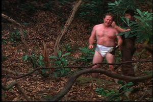 1991 Ford Bronco - A man wearing only a diaper stands in a wooded area, with another person partially visible behind him.