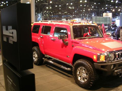 2000 Pontiac Trans Am - A red Hummer H3 SUV is displayed at an auto show with its doors open.