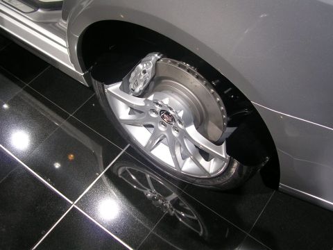2000 Pontiac Trans Am - A close-up view of a car's wheel assembly, highlighting the brake system and custom rim, reflecting on the polished floor.