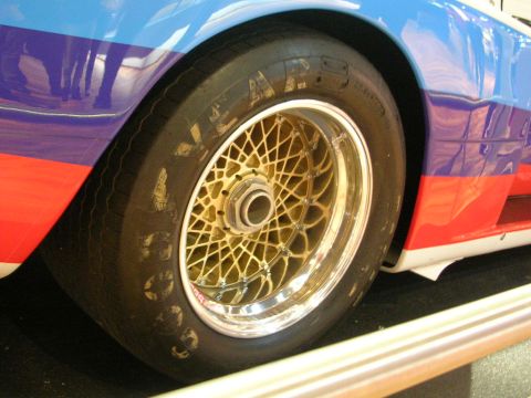 2000 Pontiac Trans Am - A close-up view of a gold mesh wheel and tire on a vehicle bold red, blue, and white racing stripes.