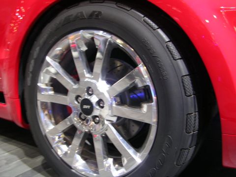 2000 Pontiac Trans Am - Close-up of a red car's wheel, a silver multi-spoke rim and a visible blue brake caliper.