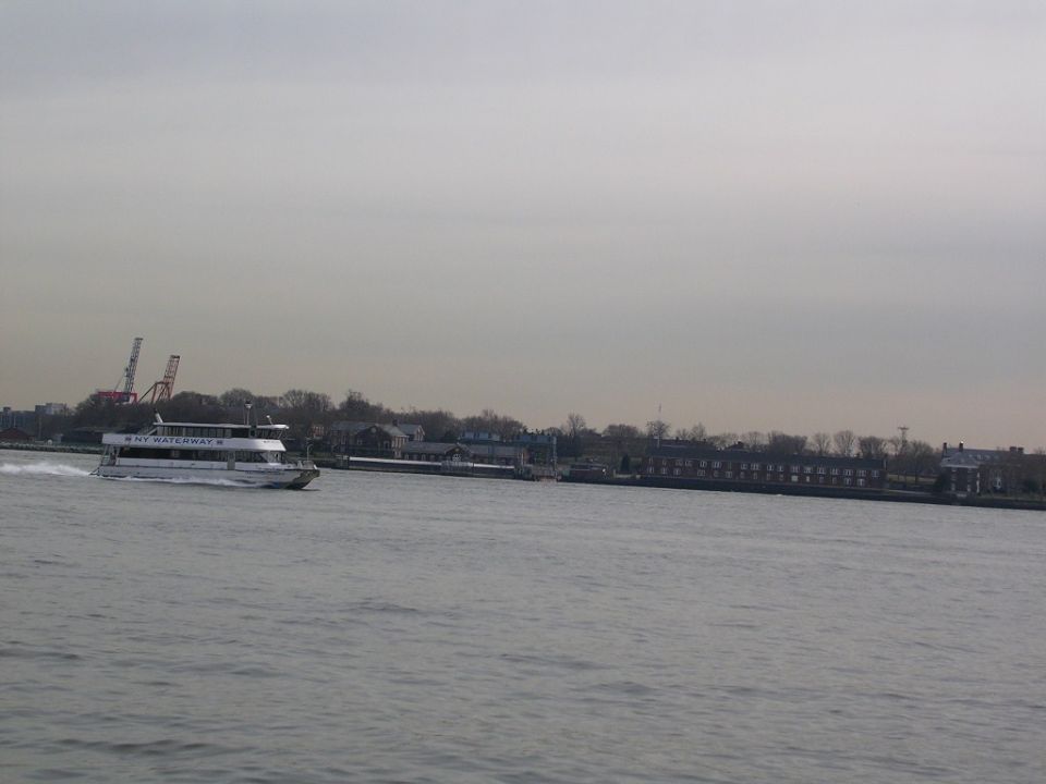 NY Waterway ferry boat moving on water with buildings and cranes in background