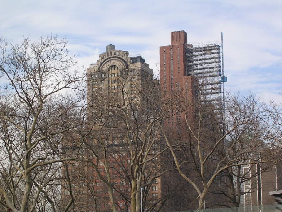 Buildings and bare trees under a cloudy sky
