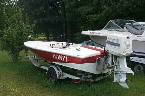 1978 Ford F-250 - A red and white Donzi boat is parked on a trailer next to another boat in a grassy area.