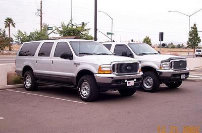 2002 Ford Excursion - Two Ford vehicles, an Excursion SUV and an F-Series truck, are parked side-by-side in a lot.