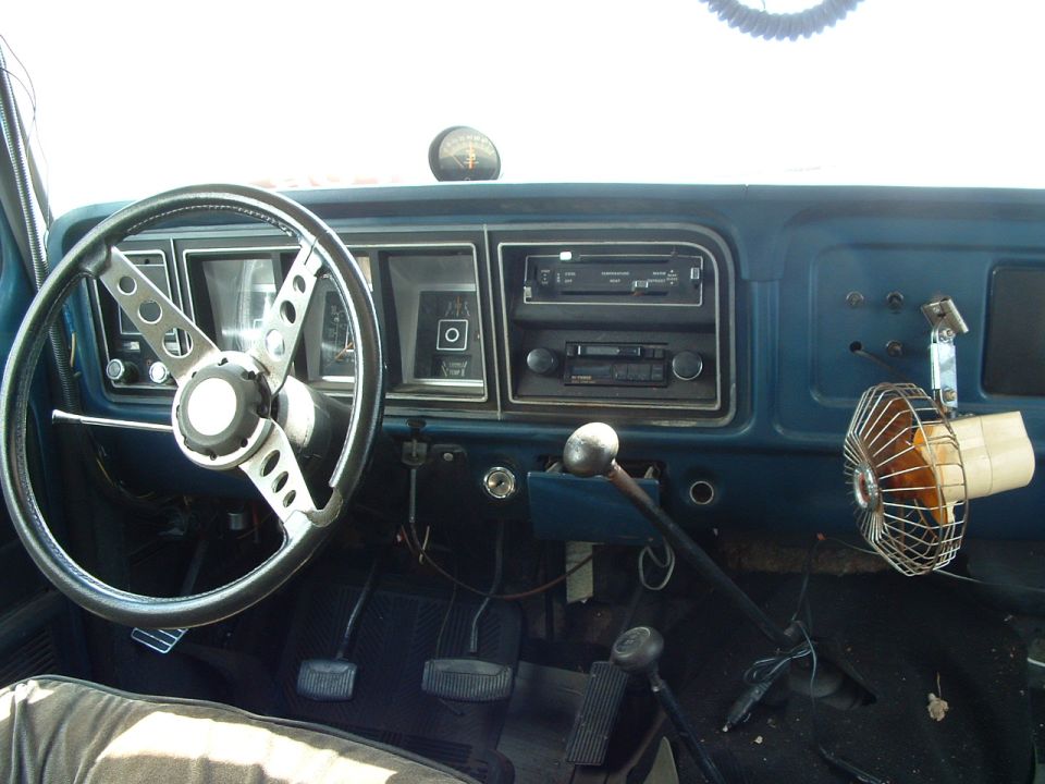 Interior view of a truck dashboard with a aftermarket steering wheel, radio, and a small fan