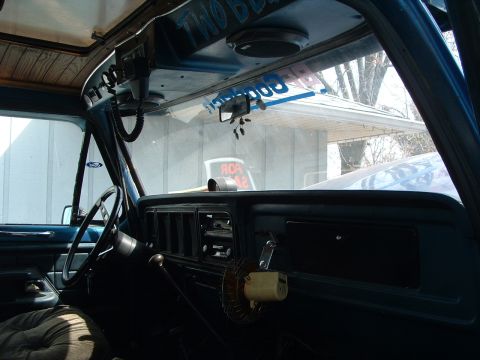 1979 Ford Bronco - The interior of a vehicle shows the dashboard, steering wheel, and a CB radio mounted near the passenger side.