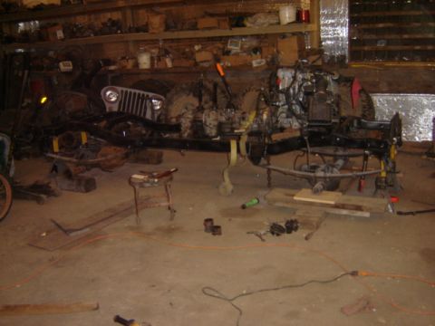 1992 Ford Bronco - Jeep CJ-5 chassis is disassembled for repair work in a garage.