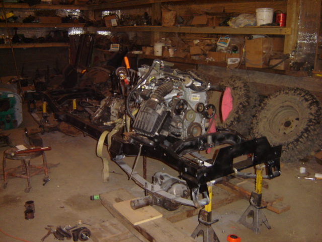 Vehicle frame on jack stands with engine installed, in a workshop