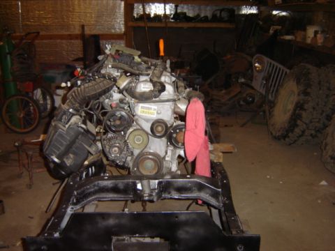 1992 Ford Bronco - An engine and chassis assembly is shown in a cluttered workshop environment.