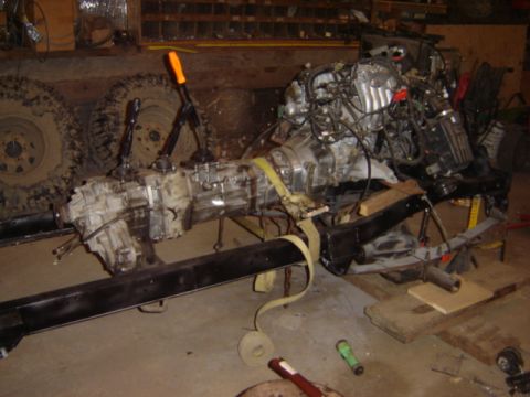 1992 Ford Bronco - Engine and transmission assembly, likely from a 4x4 vehicle, is suspended on a frame with two prominent levers forked levers.