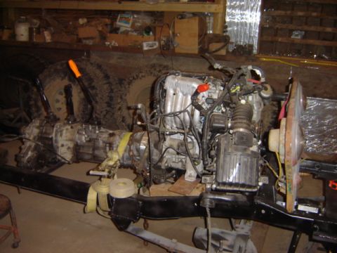 1992 Ford Bronco - The engine and transmission are mounted on the vehicle's frame, with large tires in the background.
