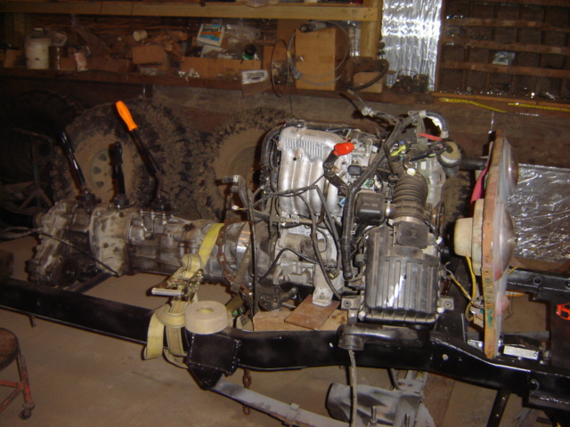 vehicle frame with engine and transmission installed, tires visible