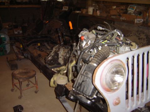 1992 Ford Bronco - A disassembled vehicle chassis and engine are visible in a cluttered workshop environment.