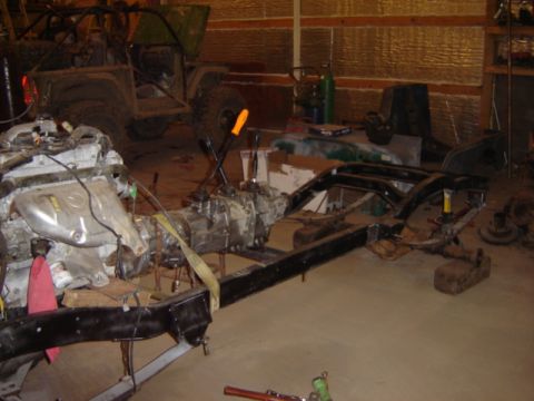 1992 Ford Bronco - Vehicle frame, engine, and transmission are laid out in a workshop. Another vehicle is in the background.