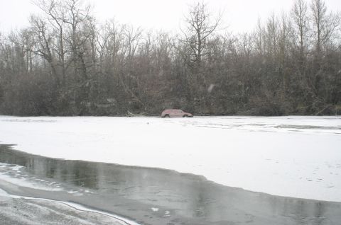 2003 Jeep TJ - A red SUV is partially submerged in ice and snow near a treeline.