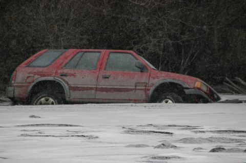 2003 Jeep TJ - A red SUV is stuck in the snow during a winter storm.