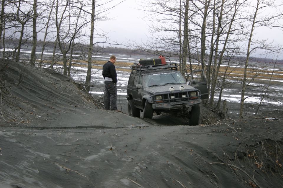 Jeep Cherokee XJ on a dirt hill with a guy standing nearby